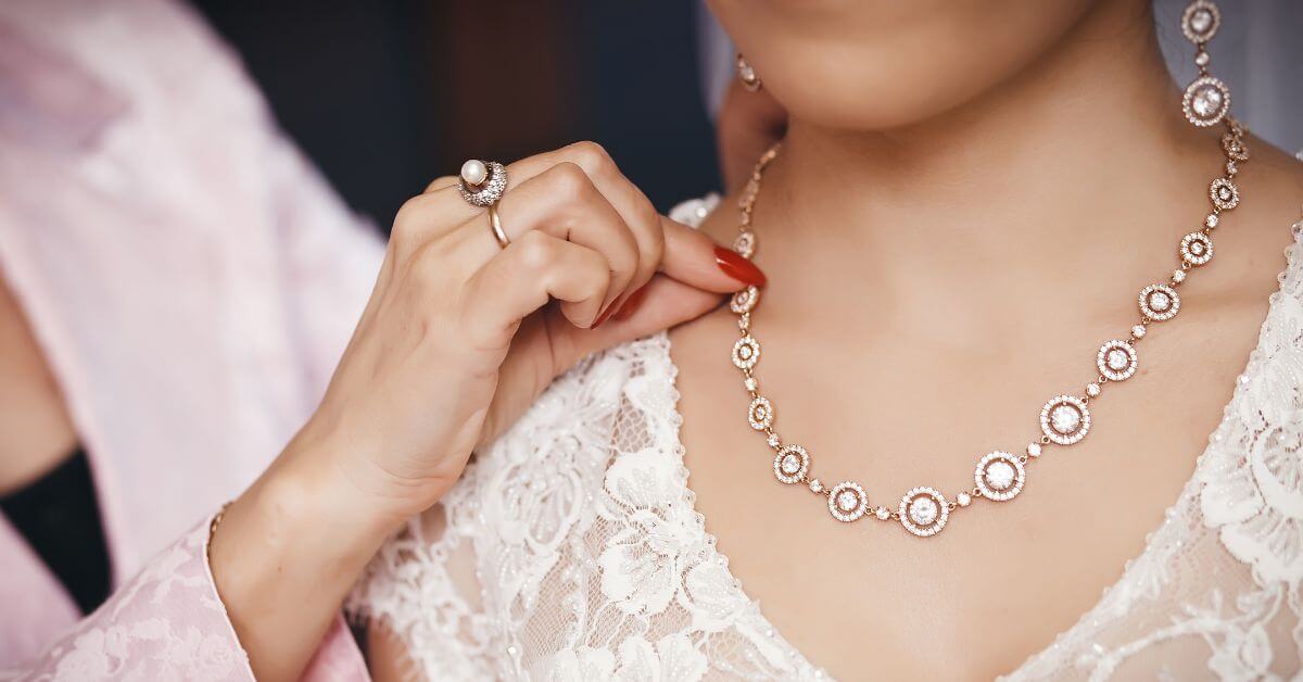 mother helping her daughter put on family heirloom jewelry on her wedding day.