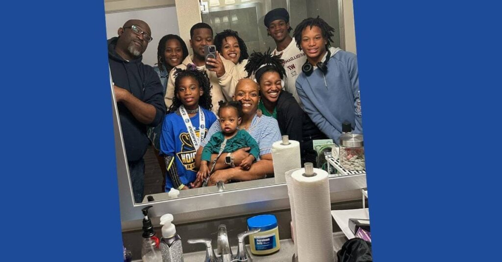 a family poses in a bathroom mirror after helping their mom shave her hair during her journey through endometrial cancer.