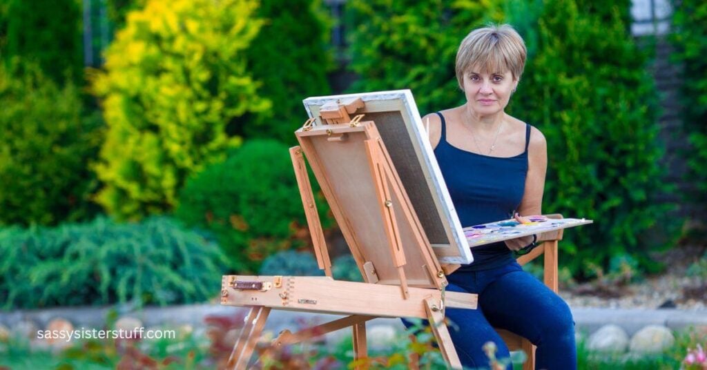 woman sitting outside painting on an easel after she overcame her fear of trying new hobbies