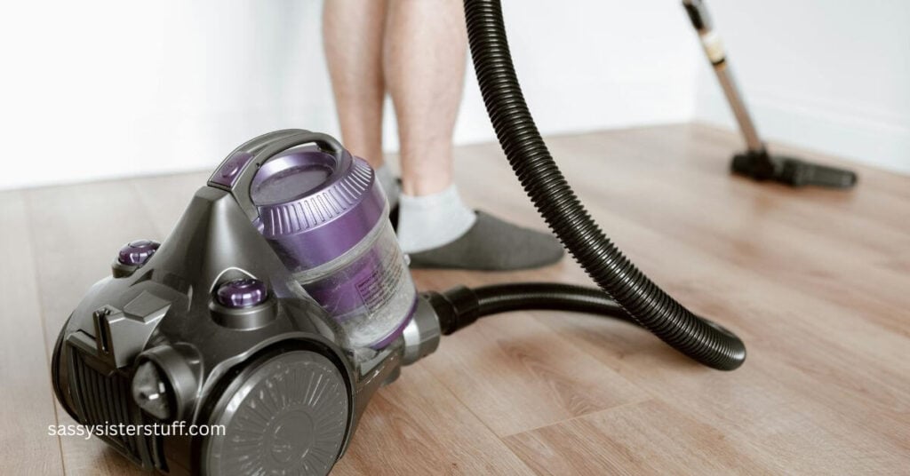 close up of someone vacuuming with a hose and extension so she doesn't have to bend over and hurt her back as she cleans.