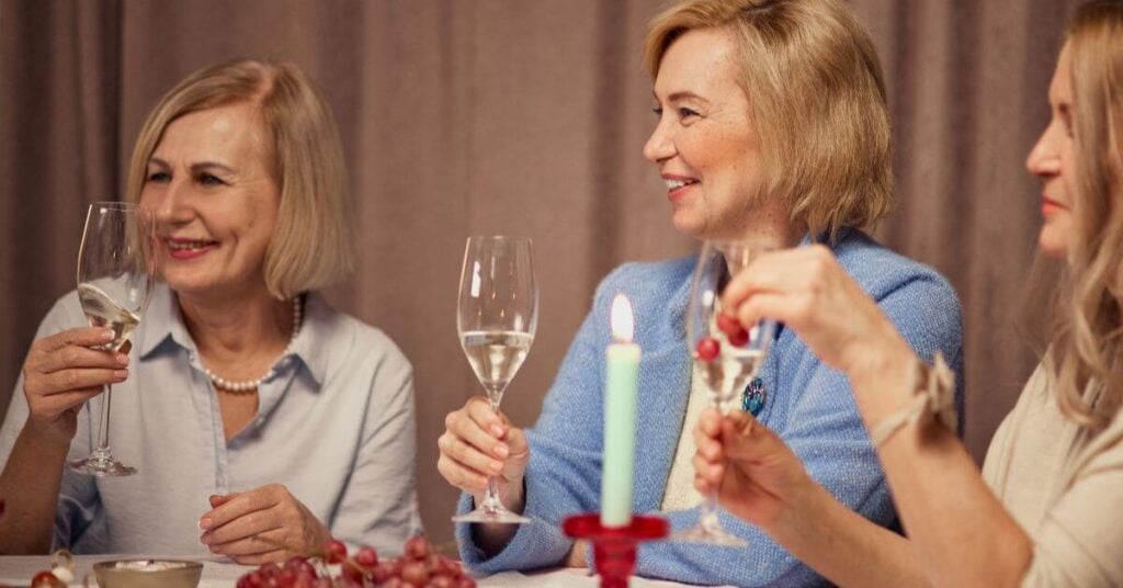 three older ladies quietly share a glass of wine together because aging changes the way we celebrate big moments in life.