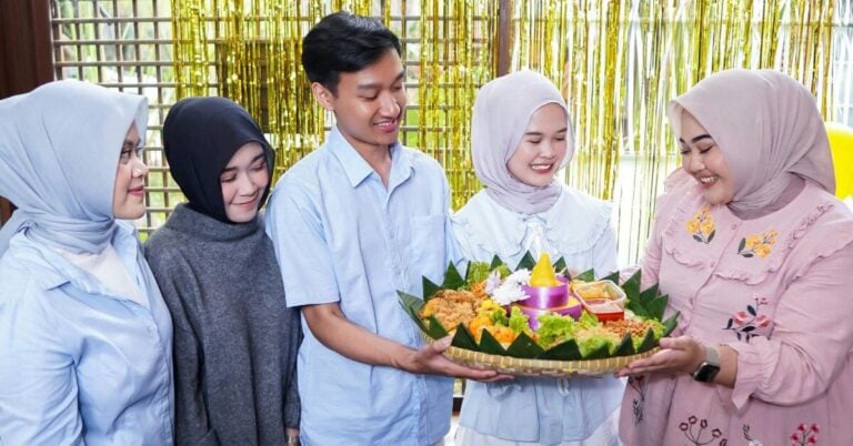 Traditional cultural birthday celebration with five friends and a food platter.