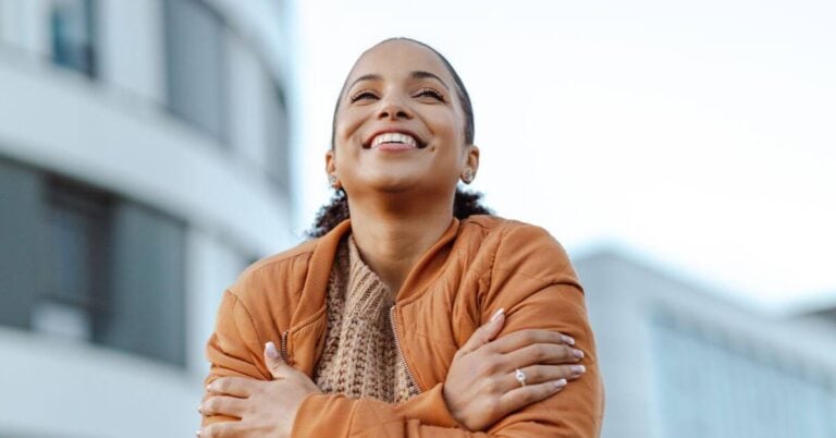 a woman smiles and gives herself a hug as she ponders finding yourself again in midlife.