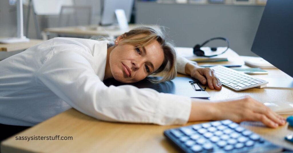 middle aged woman with her head laying on her desk because she needs a mid-day nap.