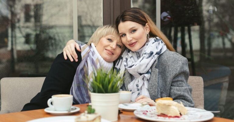 two midlife women at brunch on a street cafe pose for a picture to show what hygge means.