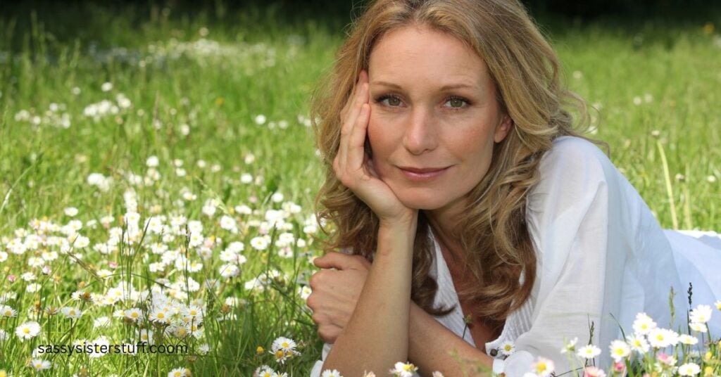 beautiful woman lies in a field of white wild flowers and ponders if life is over at 50.