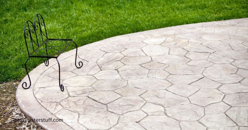 a nice curved concrete sideway with a wrought iron seat, missing cushions, sitting on the edge waiting for someone to create a fresh outdoor space here.