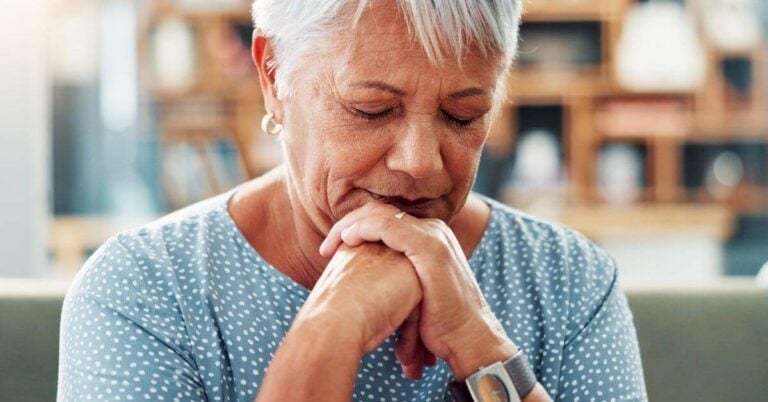 a close up of an older woman praying as part of learning how to strengthen your faith.