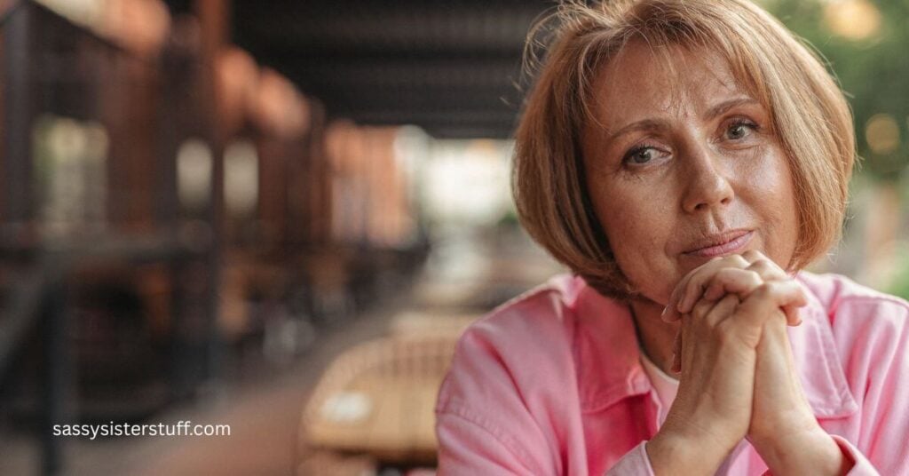 a midlife woman with her hands clasped under her chin looking pensively into the camera.
