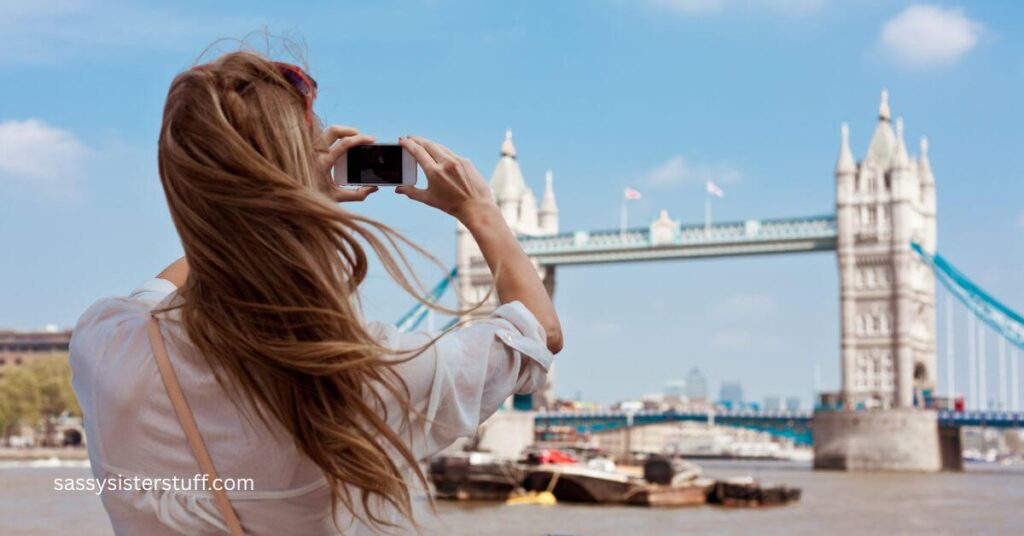 a woman takes a picture of a bridge in another country.