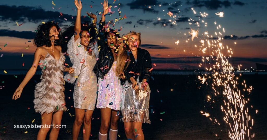 four women outside on a beautiful dark night with fireworks going off around them.