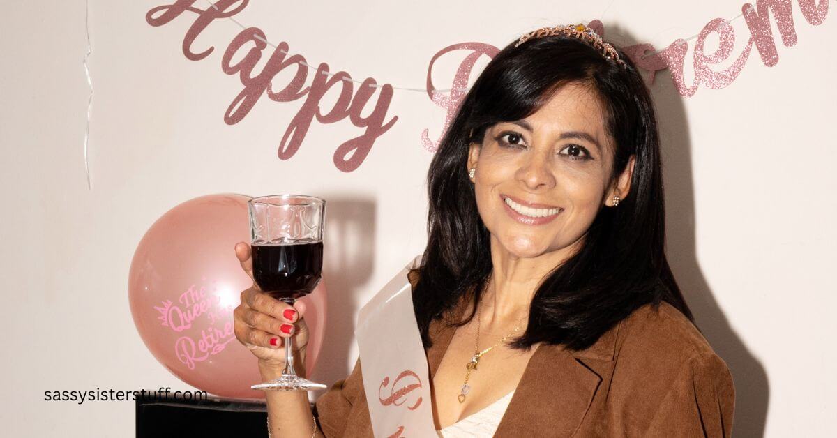 a beautiful woman raises a glass and poses for a photo in front of her happy retirement sign,